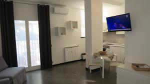 een woonkamer met een tafel en een tv aan de muur bij Karina, to the beach with terrace and private parking in Savona