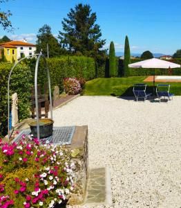 een tuin met 2 stoelen en een parasol en bloemen bij Il Casale del Nonno in Capannori