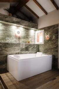 uma banheira branca num quarto com uma parede de pedra em Appart hôtel le 8 La Suite & Spa em Mâcon