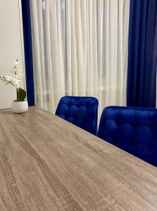 a table with two blue chairs and a vase on it at DOBA RENT Wysockiego 104 in Białystok