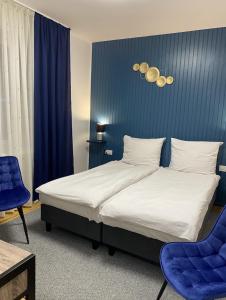 um quarto com uma cama com uma parede azul e 2 cadeiras em DOBA RENT Wysockiego 104 em Białystok