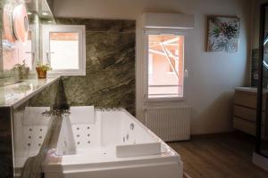 uma casa de banho com uma banheira branca e uma janela em Appart hôtel le 8 La Suite & Spa em Mâcon