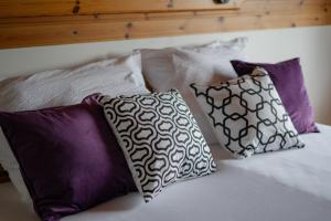 four pillows on a bed with purple and white pillows at S.A.W. Rooms in Schiefling am See