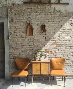 two chairs and a table in front of a brick wall at Cascina Antiche Terre in Campegine