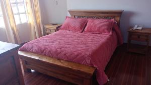 1 dormitorio con cama con edredón y almohadas rojos en SORACA MANTO REAL, en Soracá