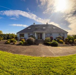 une maison blanche avec le soleil dans le ciel dans l'établissement DOONEEN HOUSE, à Killarney