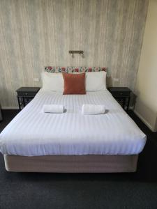 uma grande cama branca com duas almofadas em Amber Court Motel Nelson em Nelson