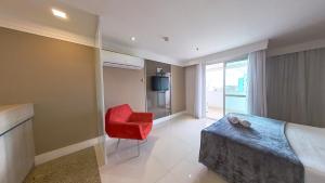 a living room with a red chair and a television at Flat no Brasília Lider, 14º Andar in Brasília