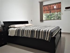 a bedroom with a bed with a striped comforter and a window at Casa de Campo Ideal para Famílias e Amigos in Quadra +62 photos