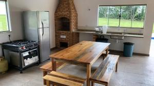 uma cozinha com uma mesa de madeira e um fogão em Sítio São Luiz, R2: Refúgio rústico na Natureza em Quadra