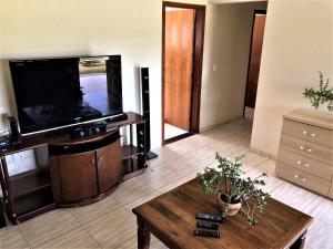 uma sala de estar com uma televisão de ecrã plano e uma mesa de centro em Sítio São Luiz, R3: Aconchego rústico na natureza em Quadra