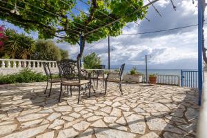 a patio with a table and chairs and the ocean at Tropical Beach "Poseidon" in Petalidi