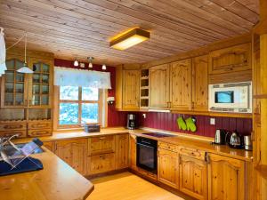 a large kitchen with wooden cabinets and a microwave at Flåm holiday home - mountain view - 1 km from Flåm in Flåm