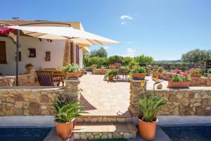 a patio with an umbrella and chairs and potted plants at Villa Pedra Moro in Alghero