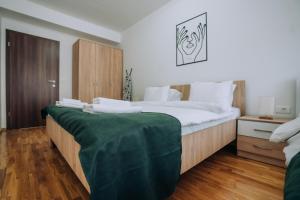 a bedroom with a large bed with a green blanket on it at Darki Apartments 2 - Very Central Stay With Free Parking in Ohrid