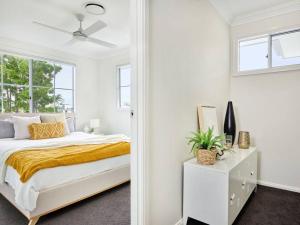 een witte slaapkamer met een bed en een raam bij Broadwater Lux home in Gold Coast