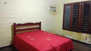 un letto rosso in una stanza con finestra di Casa de praia Vera a Caucaia