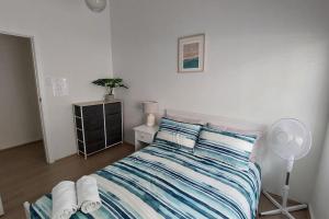 una camera da letto con un letto con lenzuola a righe e un ventilatore di 3br house, 5 min walk to beach with parking a Sydney