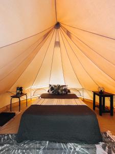 a bed in a tent with two tables at Glamping Guayaha in Lanquín