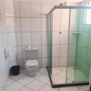 a bathroom with a toilet and a glass shower at Hotel Ita in Itaboraí