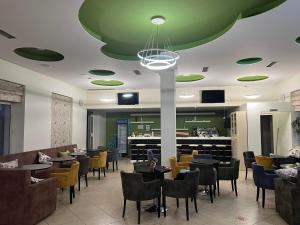 a restaurant with tables and chairs and a green ceiling at Adriatiku i Vjeter in Shëngjin