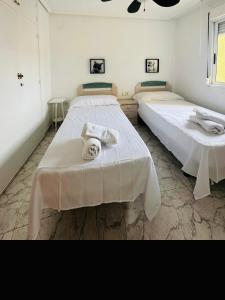 Dos camas en una habitación blanca con toallas. en Apt Diego Long term stay, en Benidorm