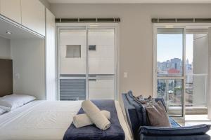 ein Schlafzimmer mit einem Bett und einem Stuhl und Fenstern in der Unterkunft Studio com garagem, ar condicionado e piscina in São Paulo + 26 Fotos