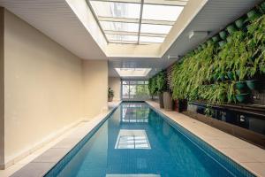 ein Hallenbad mit Pflanzen an der Wand in der Unterkunft Studio com garagem, ar condicionado e piscina in São Paulo
