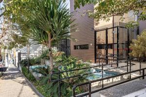 einen Garten mit einer Palme und einem Zaun in der Unterkunft Studio com garagem, ar condicionado e piscina in São Paulo
