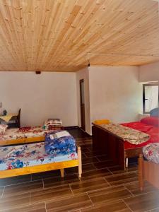 een kamer met 3 bedden en een houten plafond bij Villa Silvester in Hardedaj