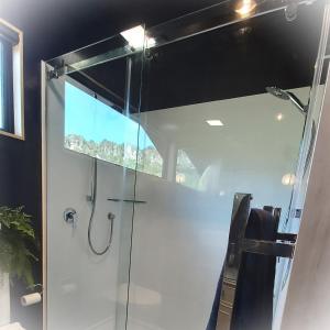 uma cabina de duche em vidro numa casa de banho com uma janela em Ripples Retreat - Riverside em Piopio