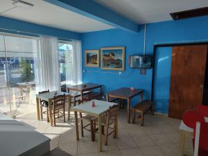 um restaurante com mesas e cadeiras e uma parede azul em Pousada Catarina em Biguaçu