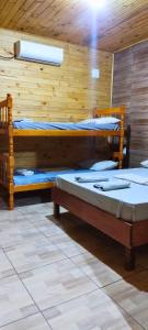 two beds in a room with wooden walls at Hotel Alvorada in Alegrete