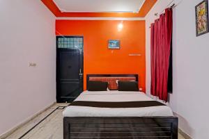 a bedroom with a bed with an orange wall at OYO Flagship Drip Stay Inn in Lucknow