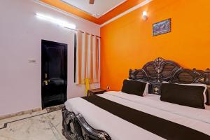 1 dormitorio con 1 cama grande y pared de color naranja en OYO Flagship Drip Stay Inn en Lucknow
