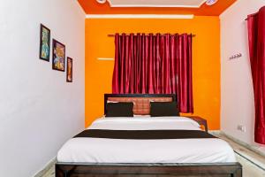 1 dormitorio con 1 cama con paredes de color naranja y cortinas rojas en OYO Flagship Drip Stay Inn en Lucknow