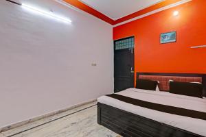 a bedroom with a bed with an orange wall at OYO Flagship Drip Stay Inn in Lucknow