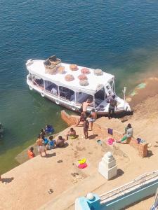 eine Gruppe von Menschen am Strand neben einem Boot in der Unterkunft ABAZIDO Nubian Guest House in Assuan