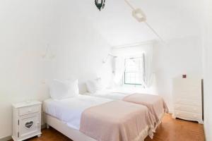 1 dormitorio blanco con 2 camas y ventana en Quinta de Cima,No campo é Assim, en Vila Franca de Xira