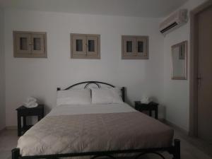 1 dormitorio blanco con 1 cama y 2 ventanas en stoudios en Naxos