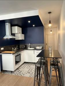 a kitchen with white cabinets and a blue wall at Le quarante neuf in Saint-Amand-Montrond