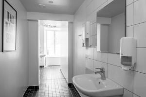 Un baño blanco con lavabo y espejo. en Castle House Inn, en Estocolmo