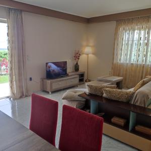 a living room with a couch and a tv at Villa Chryssi in Áyios Ioánnis