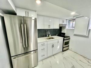 a kitchen with white cabinets and a stainless steel refrigerator at Basement Unit 25-Minute Downtown in Toronto