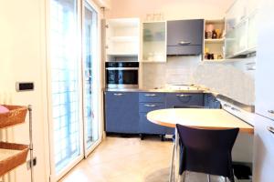 cocina con armarios azules, mesa y sillas en MiMa mare e centro en Milano Marittima