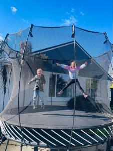 Duas crianças estão a saltar num trampolim. em Family-Friendly, Airport 6 mins, Spacious with Garden em Christchurch