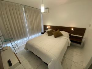 1 dormitorio con cama blanca y ventana en Departamento Don Miguel Claro, en Santiago