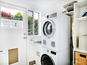 een witte wasruimte met een wasmachine en droger bij Broadwater Lux home in Gold Coast