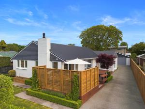 uma casa branca com uma cerca à frente. em Family-Friendly, Airport 6 mins, Spacious with Garden em Christchurch