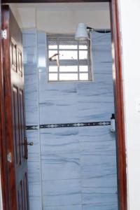 een blauwe badkamer met een raam en een deur bij Ecohome 5 wilderness within sight of the Airport in Nairobi